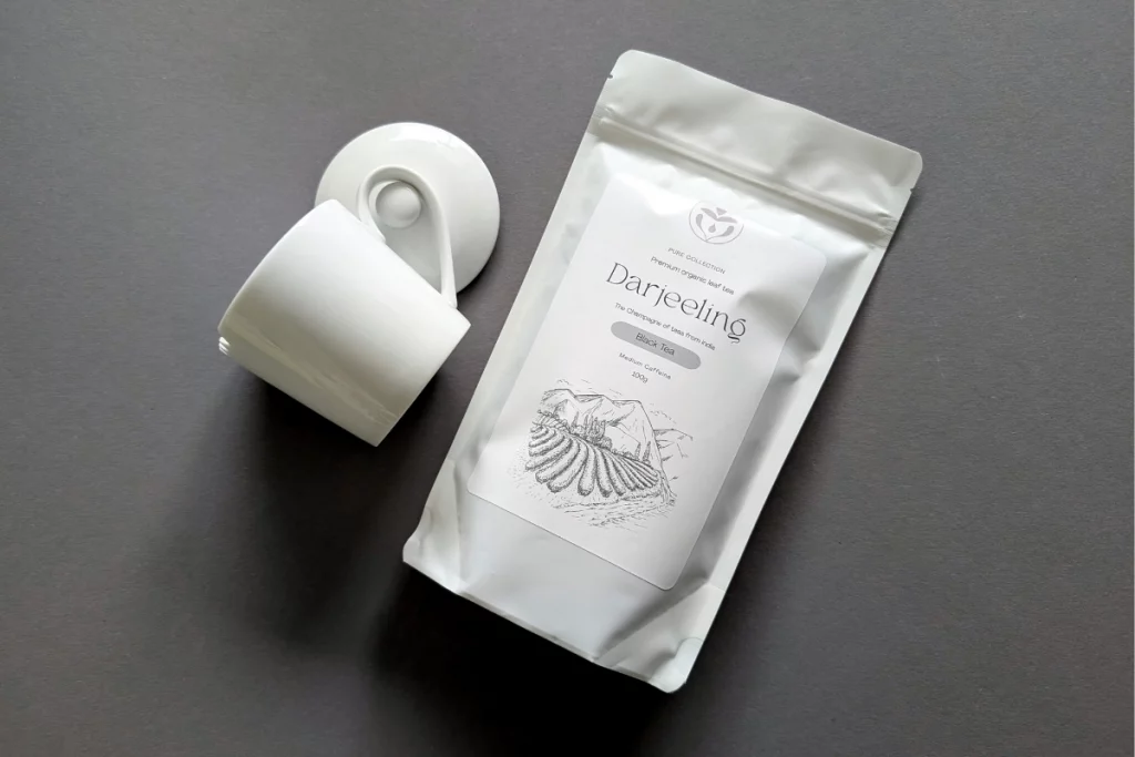 Erinora Darjeeling Tee mit Teetasse und Verpackung auf grauem Hintergrund