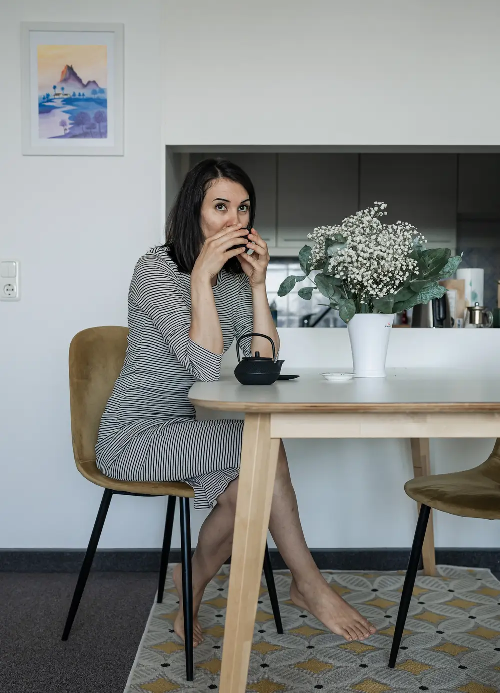 Elegante Frau sitzt am Tisch und trinkt während einer ruhigen Pause biologischen losen Tee