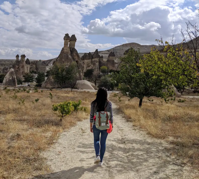 Wanderin mit Rucksack auf einem Feldweg durch eine felsige Landschaft