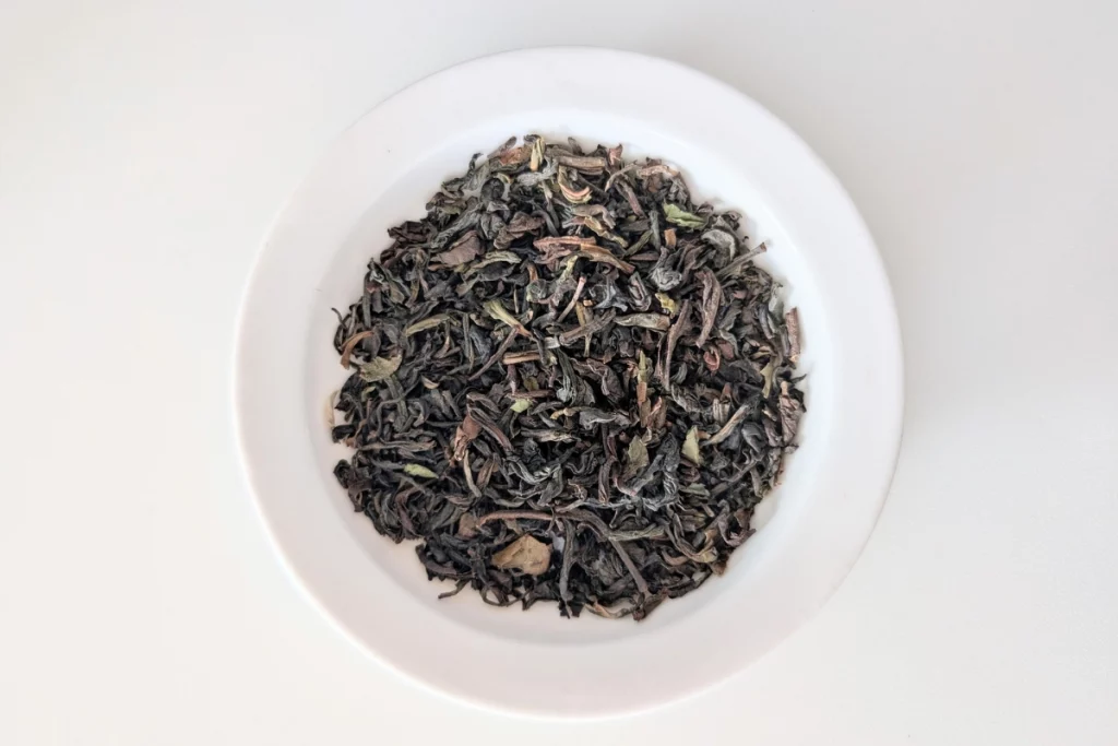 Foglie di tè Darjeeling sfuse viste da vicino in una ciotola bianca